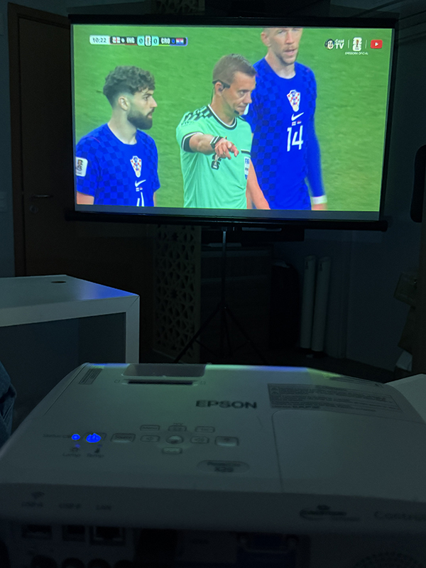 Projeção de jogo de futebol em tela instalada em ambiente escuro